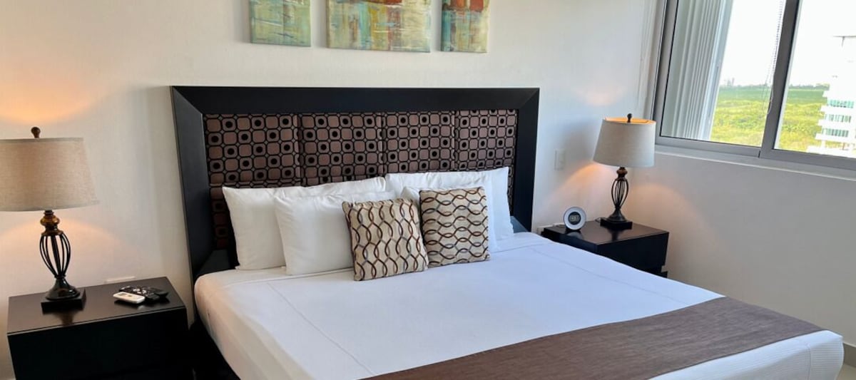 Recámara con cama king de la suite deluxe de una recámara en Suites Malecón Cancún (hasta 3 personas)